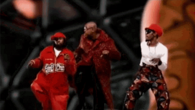 a group of men are dancing together and one of them is wearing a red jacket that says eazy e