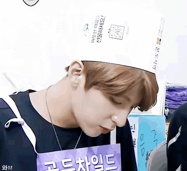 a man wearing a chef 's hat has a purple apron around his neck with korean writing on it
