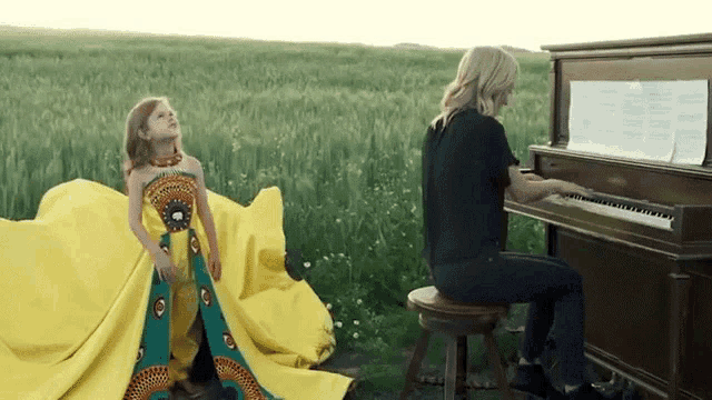 a woman is playing a piano while a little girl is standing next to her