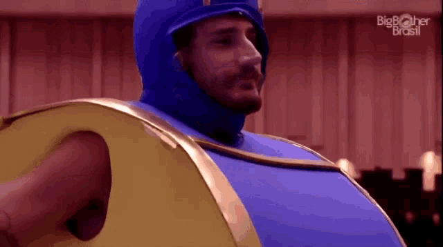 a man is wearing a blue and yellow costume with the big brother brasil logo on the bottom