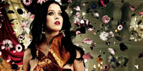 a woman in a dress is surrounded by flowers flying in the air .