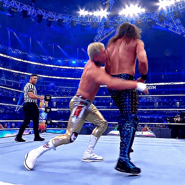 two men are wrestling in a ring with a referee and a sign that says w