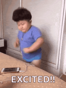 a little boy is dancing on a bed next to a phone that says excited