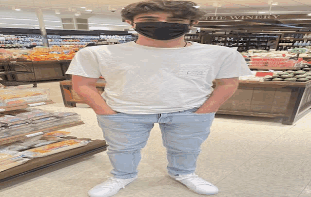 a man wearing a mask stands in front of a winery section of a grocery store
