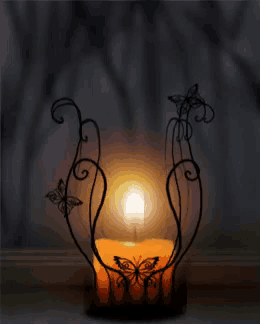a candle is lit in a candle holder with butterflies