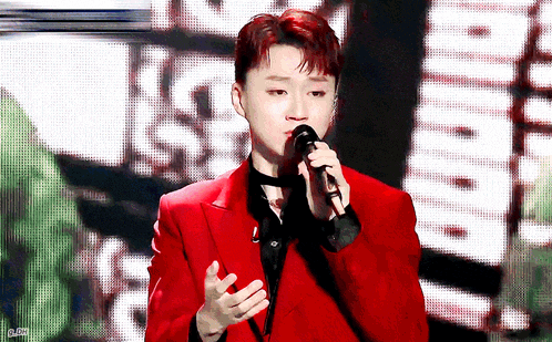 a man in a red suit singing into a microphone