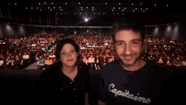 a man and a woman are standing in front of a crowd and the words titre are on the bottom