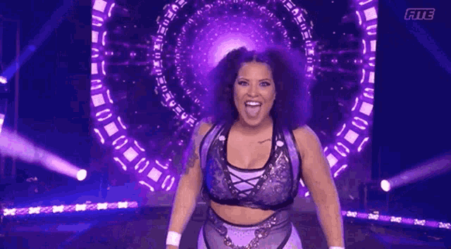 a woman is standing on a stage in front of a large purple screen .