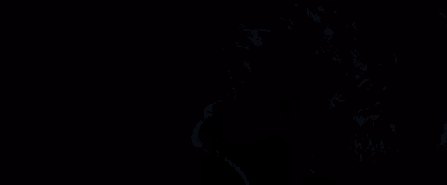 a close up of a man 's face in a dark room with his eyes closed and his mouth open .