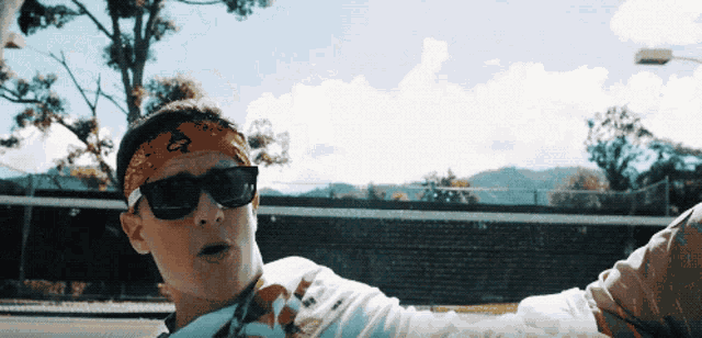 a man wearing sunglasses and a bandana with the letter o on it