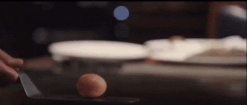 a person is cutting an egg on a cutting board with a knife