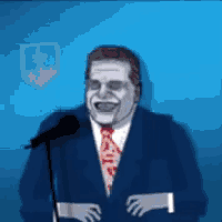 a man in a suit and tie is smiling while speaking into a microphone