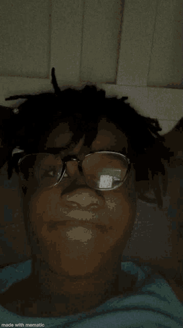 a person wearing glasses and dreadlocks is laying down