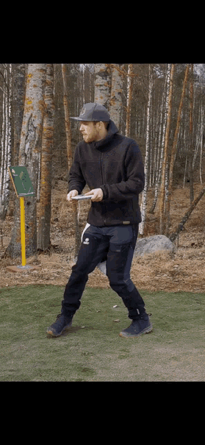 a man in a black jacket and black pants holds a frisbee