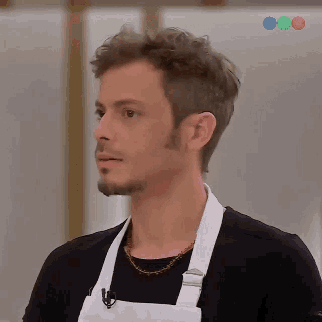 a man wearing a black shirt and a white apron is looking at something