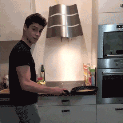 a man is cooking in a kitchen with a stainless steel oven