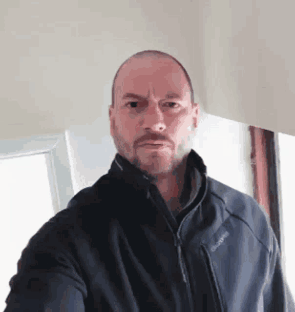 a bald man with a beard is wearing a jacket that says quechua