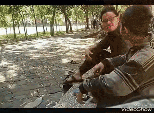 a man and a woman are sitting on a bench in a park talking .
