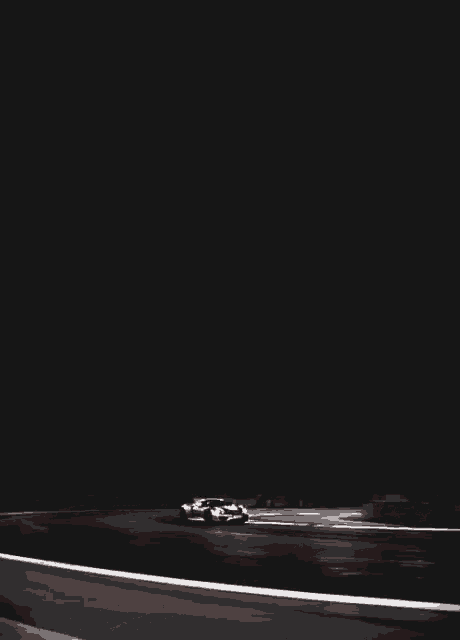 a car is driving down a road at night with a black background