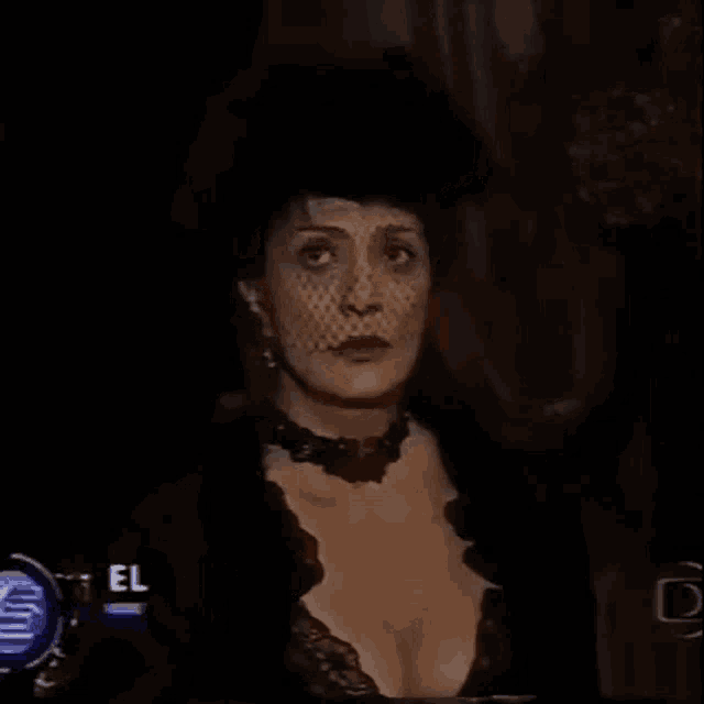 a woman in a black dress and hat is standing in a dark room with the name eliane giar on the screen .