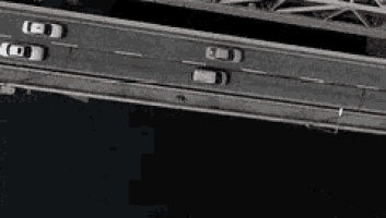an aerial view of a bridge over a body of water with cars driving on it .