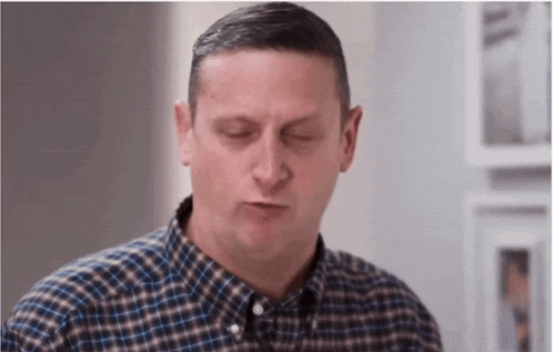 a man wearing a plaid shirt is making a funny face .