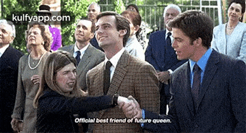 a woman is shaking hands with a man in a suit while a group of people watch .