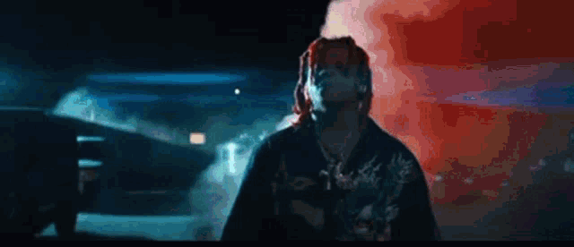 a man with dreadlocks is covering his face with his hands in front of a red and blue background .