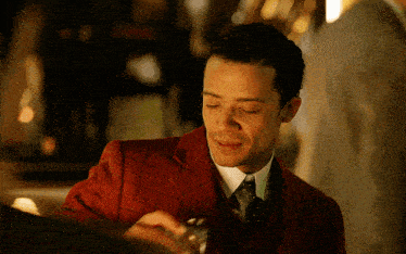 a man wearing a red suit and tie is smiling