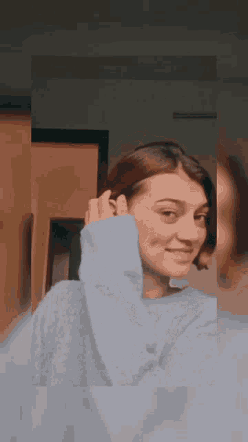 a woman wearing a blue sweater is taking a picture of herself