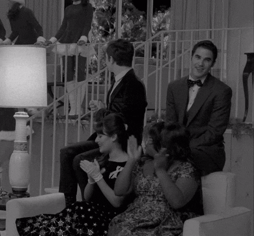 a black and white photo of a group of people sitting around a lamp