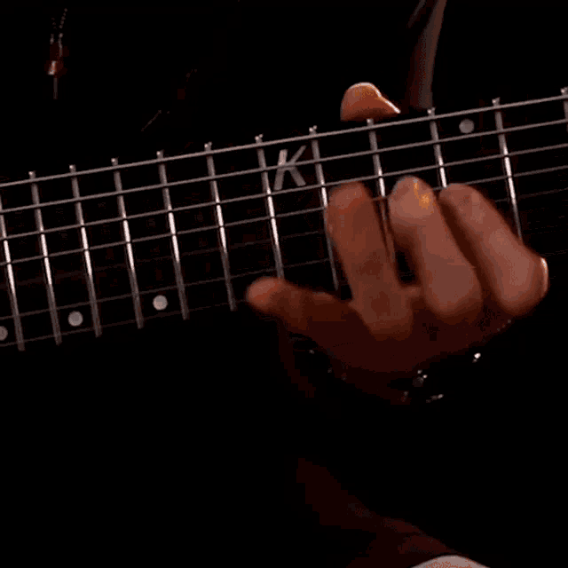 a person playing a guitar with the letter k on it