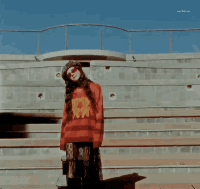 a woman in a red and black striped sweater stands on a set of steps
