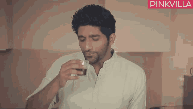 a man drinking from a glass with pinkvilla written on the bottom