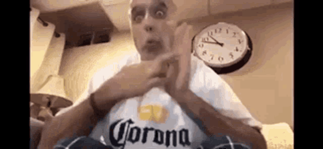 a man wearing a corona shirt is sitting on a couch .