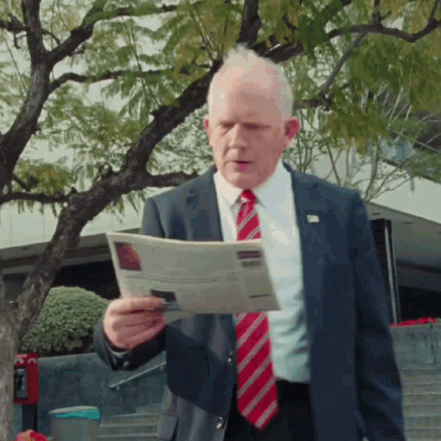 a man in a suit is reading a newspaper