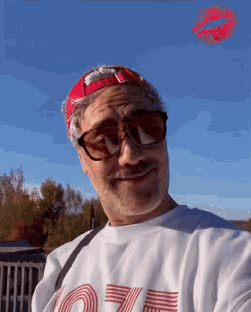 a man wearing sunglasses and a shirt that says o7e is taking a selfie