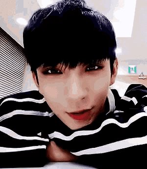a young man wearing a black and white striped shirt is laying down on a table .
