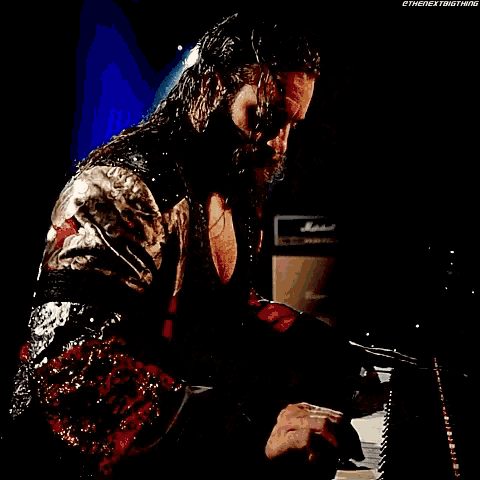 a man with a beard is playing a piano in a dark room .