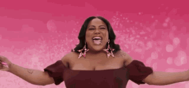 a woman in a red dress and earrings is laughing with her arms outstretched .