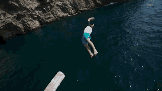 a person is jumping into a body of water from a cliff