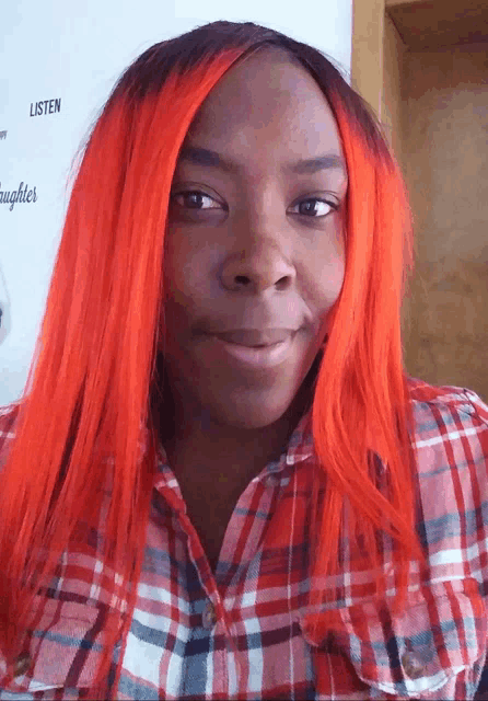 a woman with red hair is smiling in front of a sign that says listen and daughters