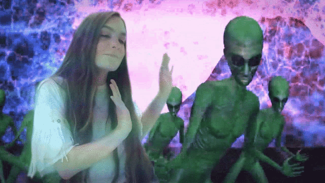 a woman is standing in front of a group of aliens