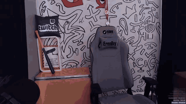 a hawk gaming chair sits in front of a wall with a pillow that says twitch on it