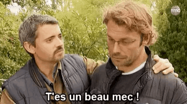 two men are standing next to each other and talking to each other .