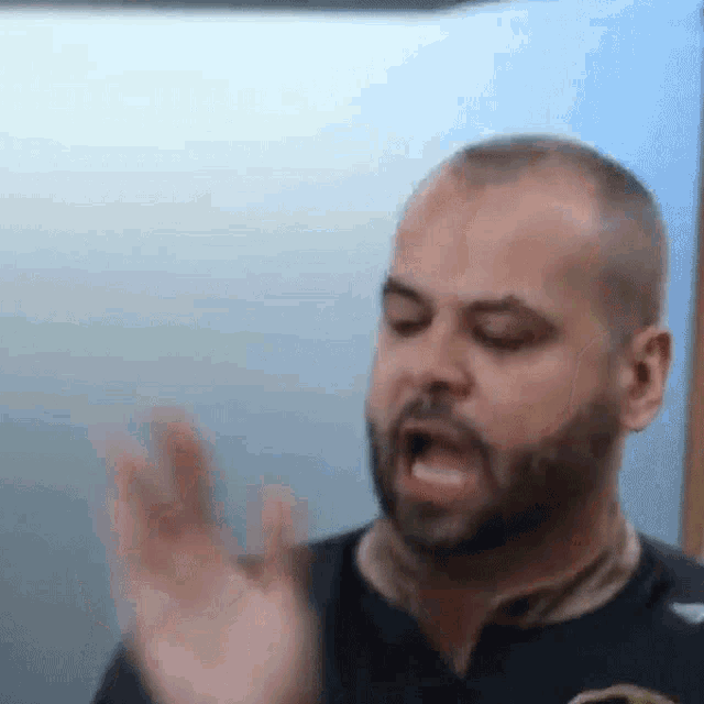 a man with a beard and a black shirt is making a funny face .