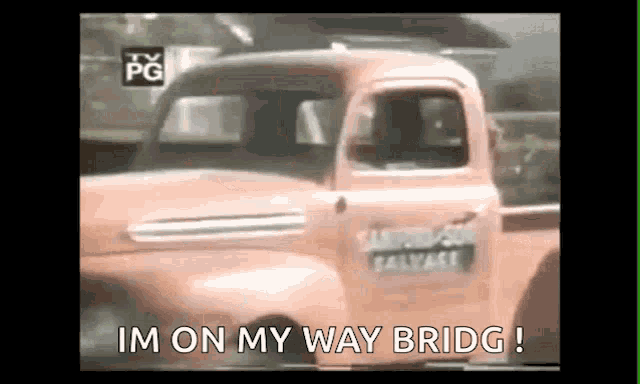 a pink truck is driving down a road with the words `` im on my way bridge '' written on it .