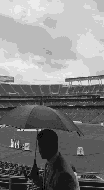 a man holding an umbrella in front of a stadium that has a sign that says ' nfl ' on it