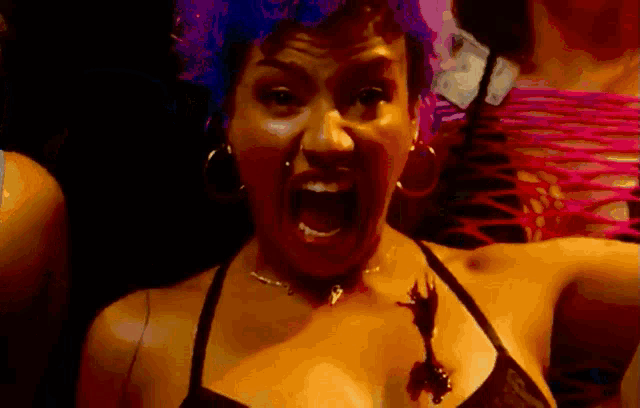a woman in a black bra and earrings is screaming
