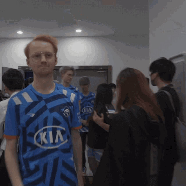 a man in a blue kia jersey stands in a crowd